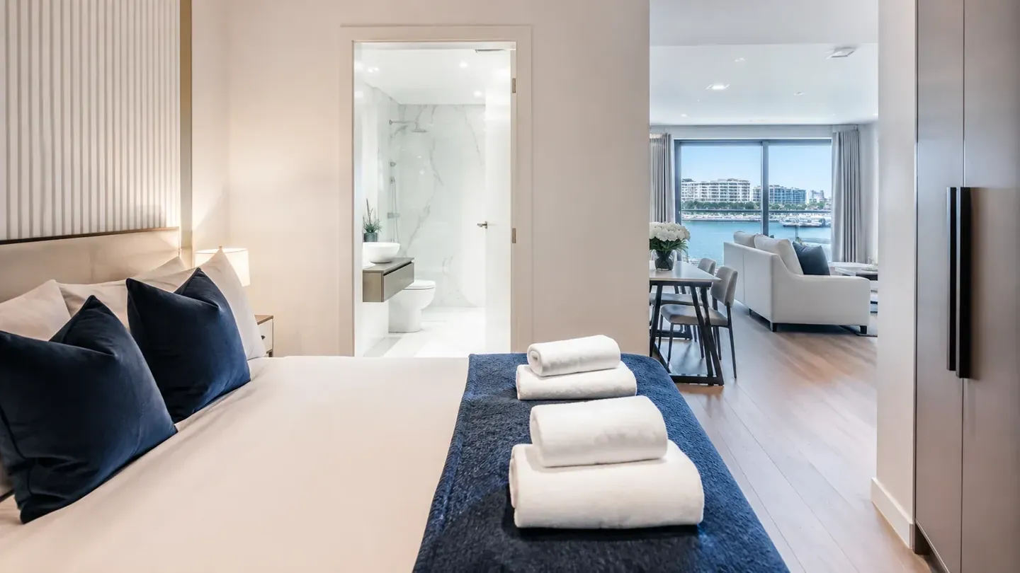 Besprijekorno uređena spavaća soba apartmana s uredno složenim ručnicima i pogledom na more.